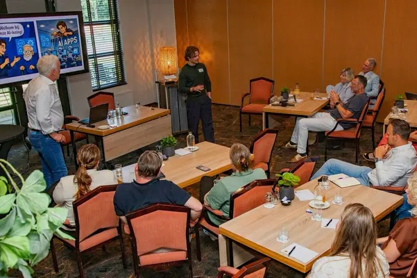 Twee sprekers openen een AI-lezing voor een groep deelnemers aan tafels